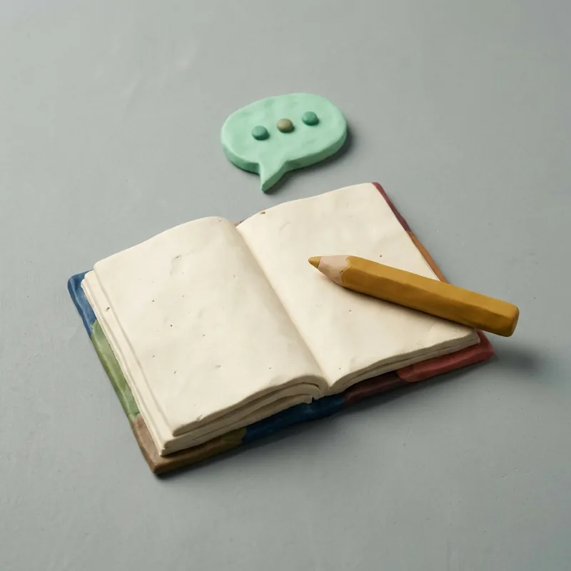 Klei-illustratie: een leeg notitieblok met een potlood en een spreekwolkje met drie puntjes.